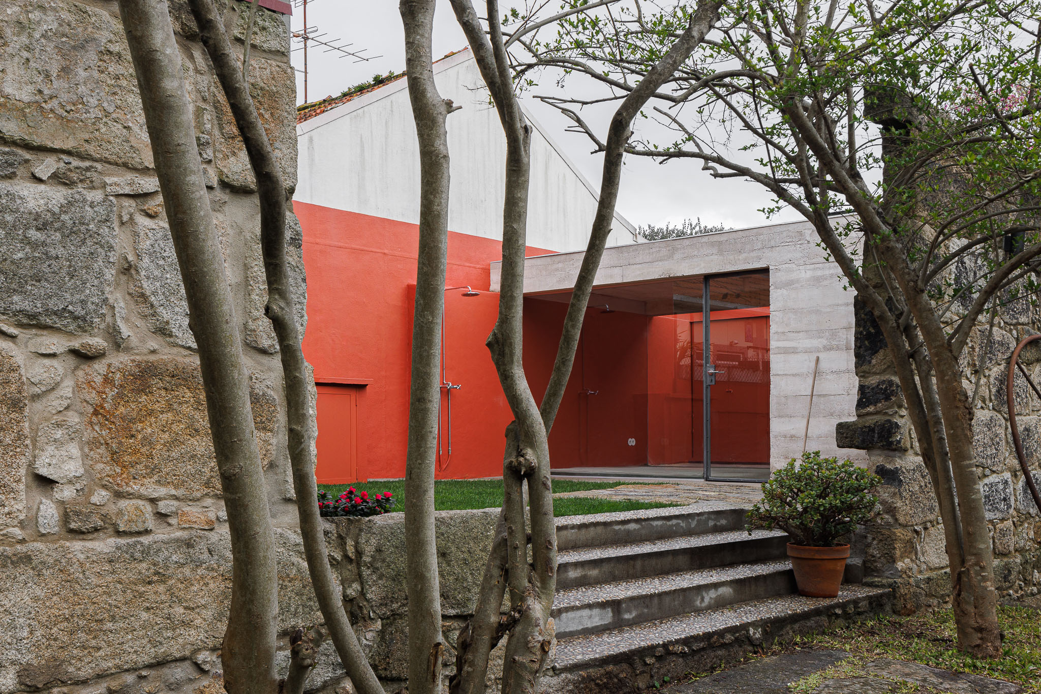 The combination of white concrete structures and surfaces with bright red hues becomes the character of the Garden Pavilion has a green courtyard on the outer side