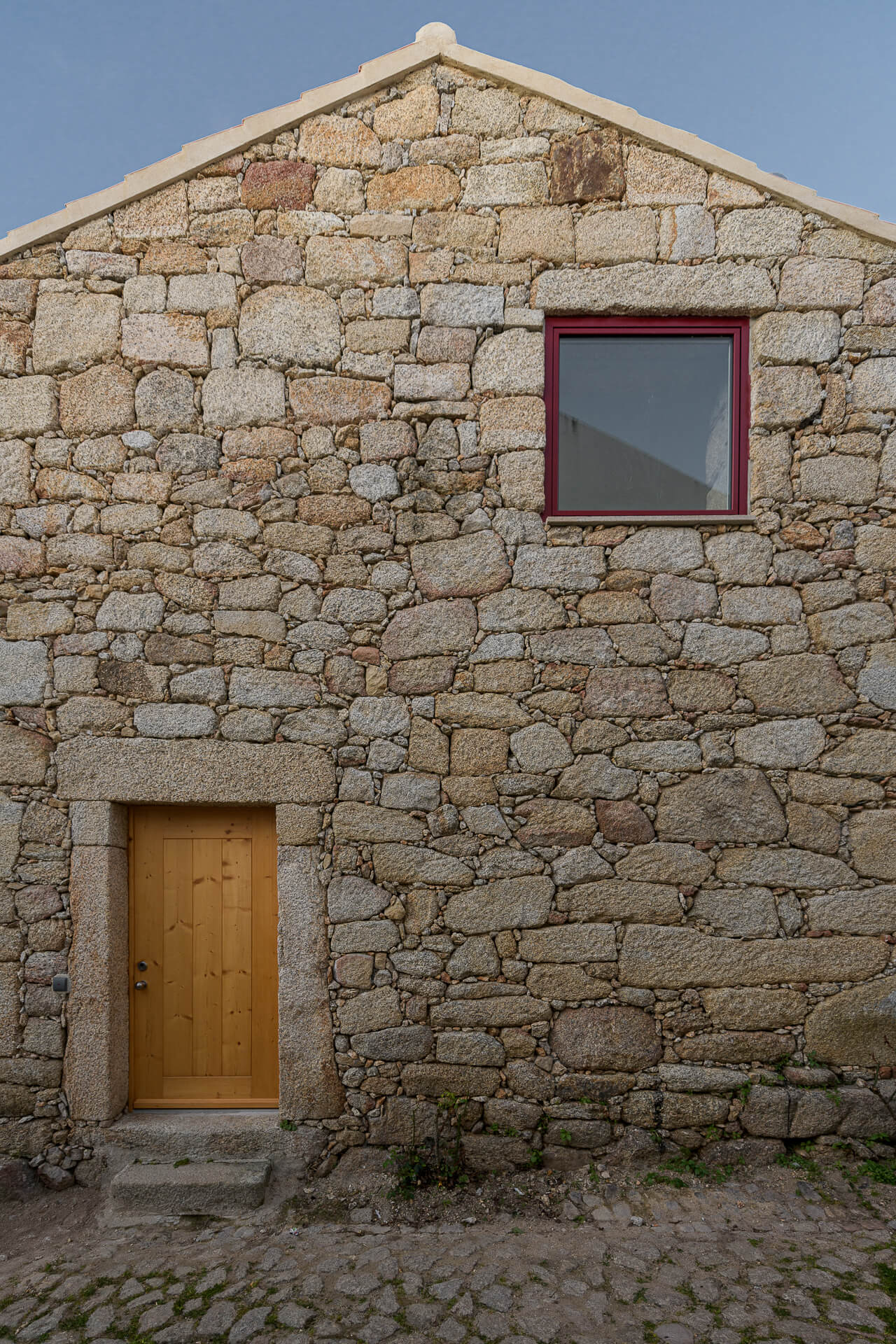 The exposed granite wall becomes the strong character of the exterior of this house