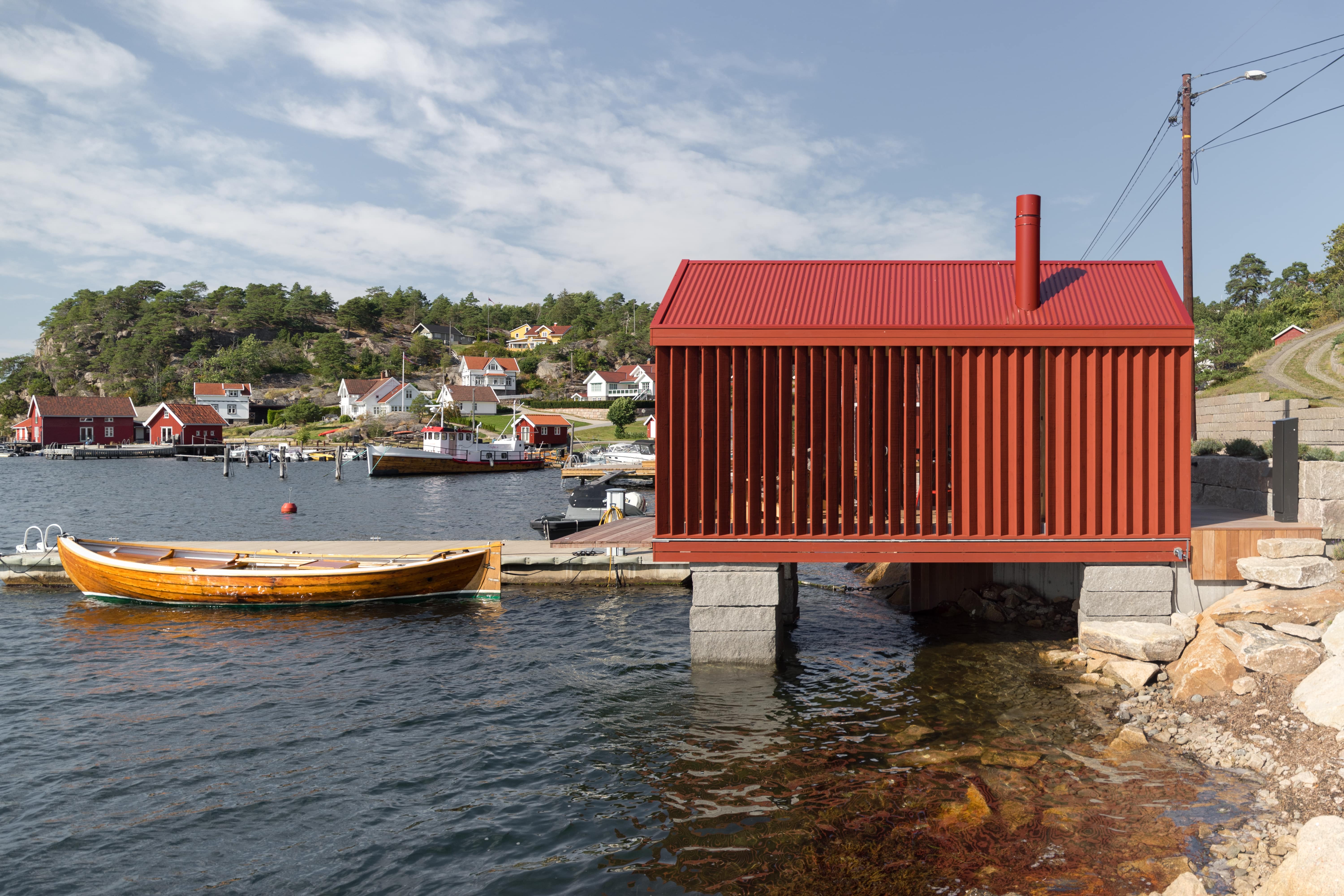 Badehus stands on a galvanized steel frame structure with red-painted cladding and tin roof