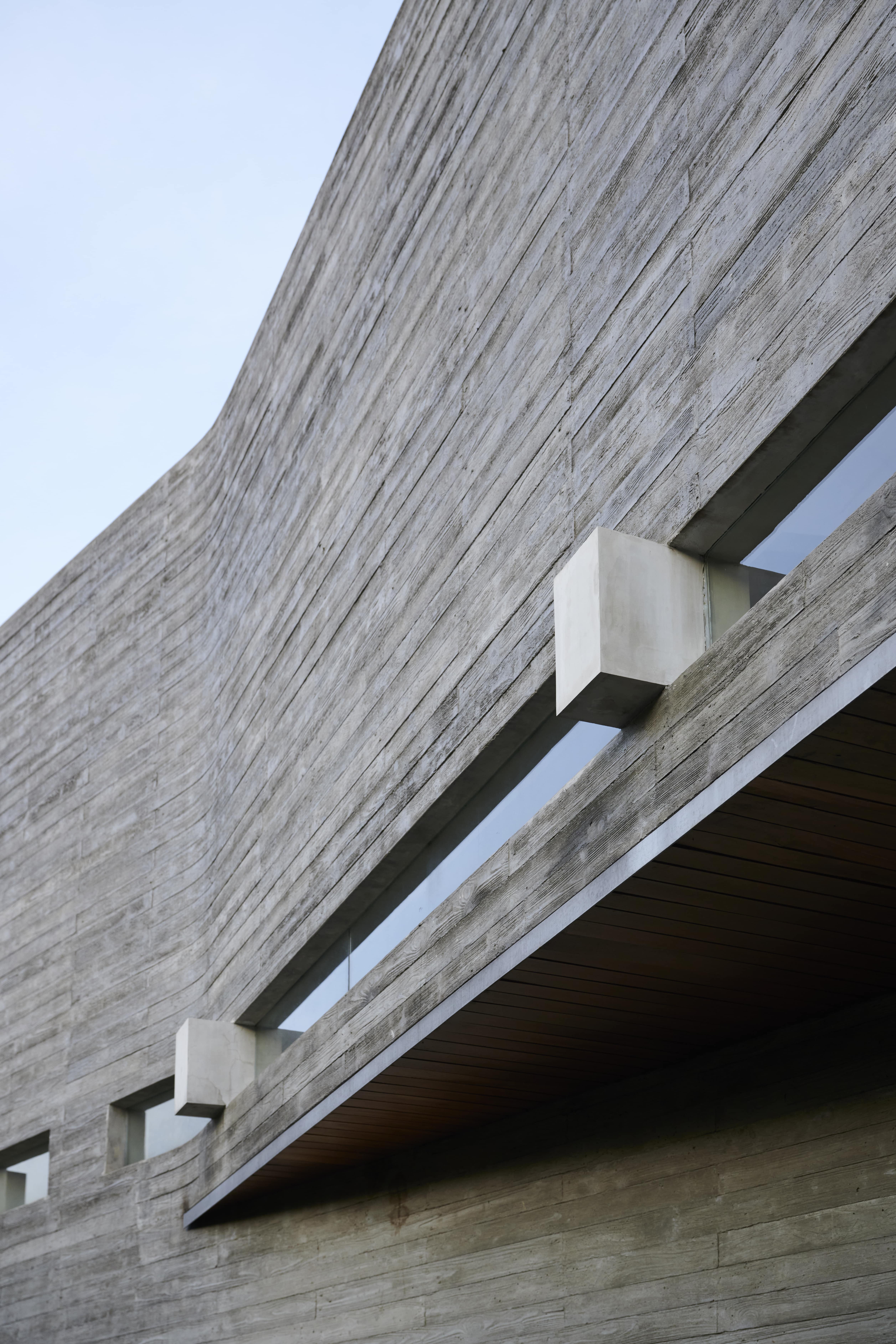 The use of wood-textured exposed concrete material for the outer surface of the house