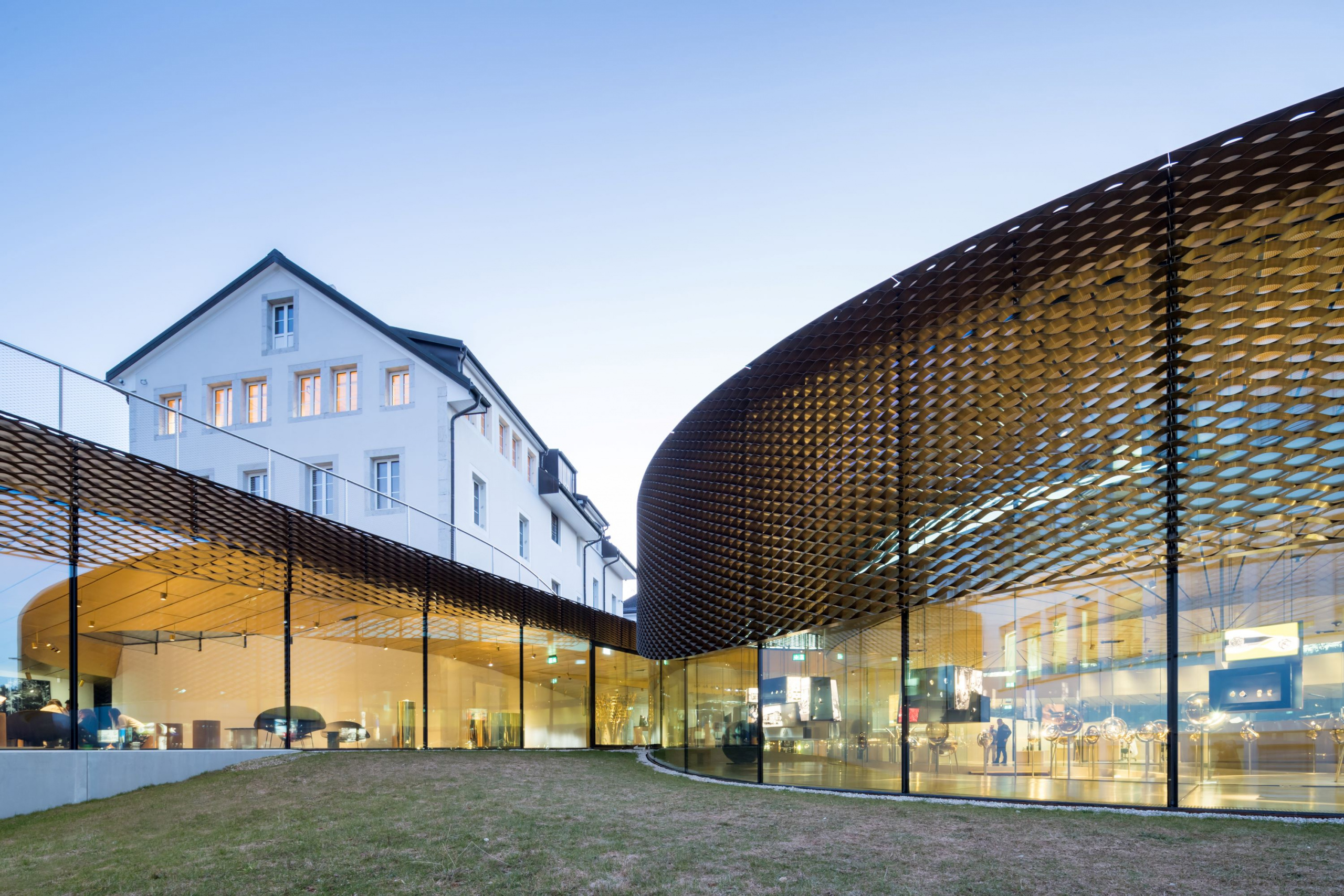 The outer surface of the curved walls of the museum is layered with brass mesh