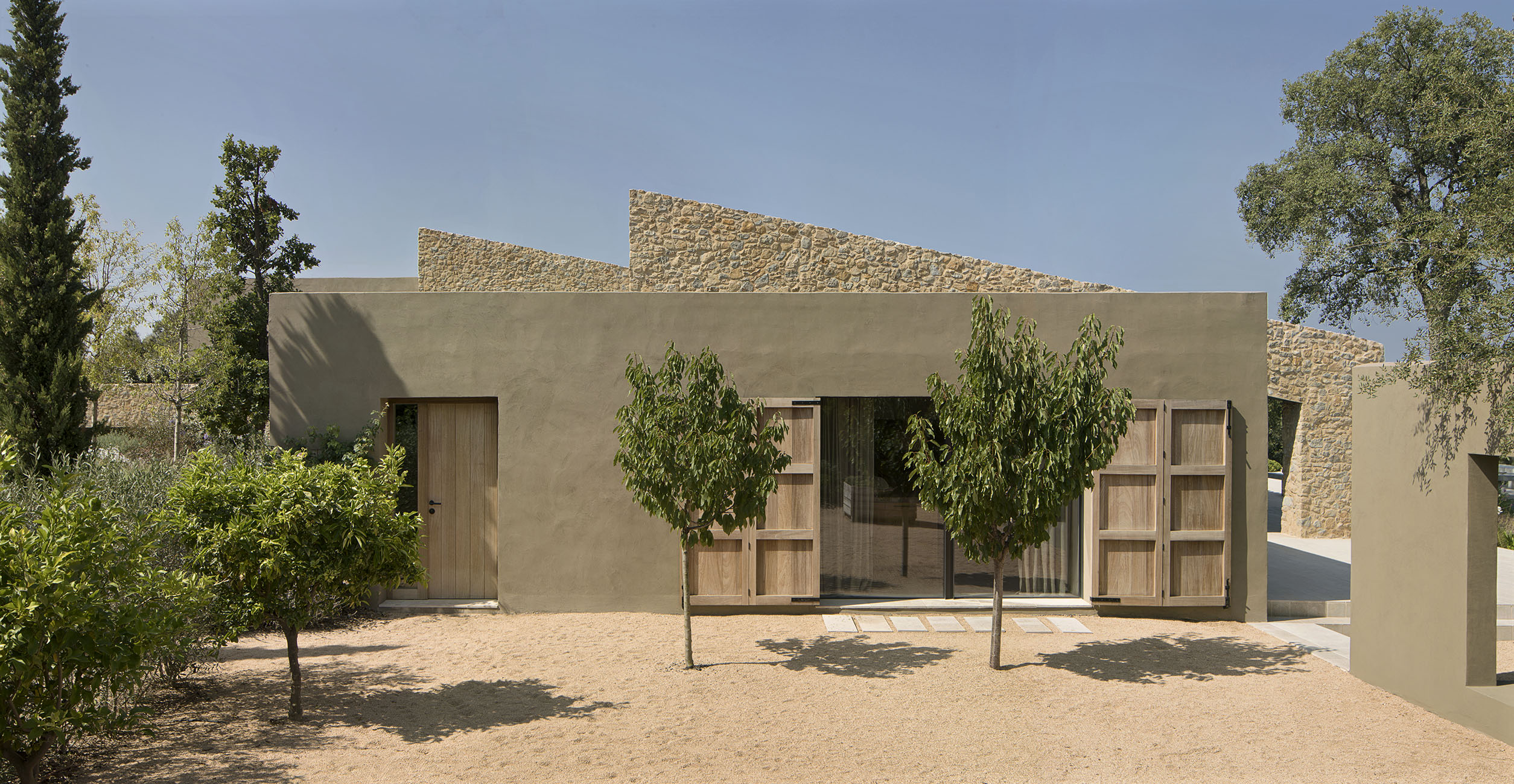 The exterior walls of the house feature a blend of natural stone material and lime stucco