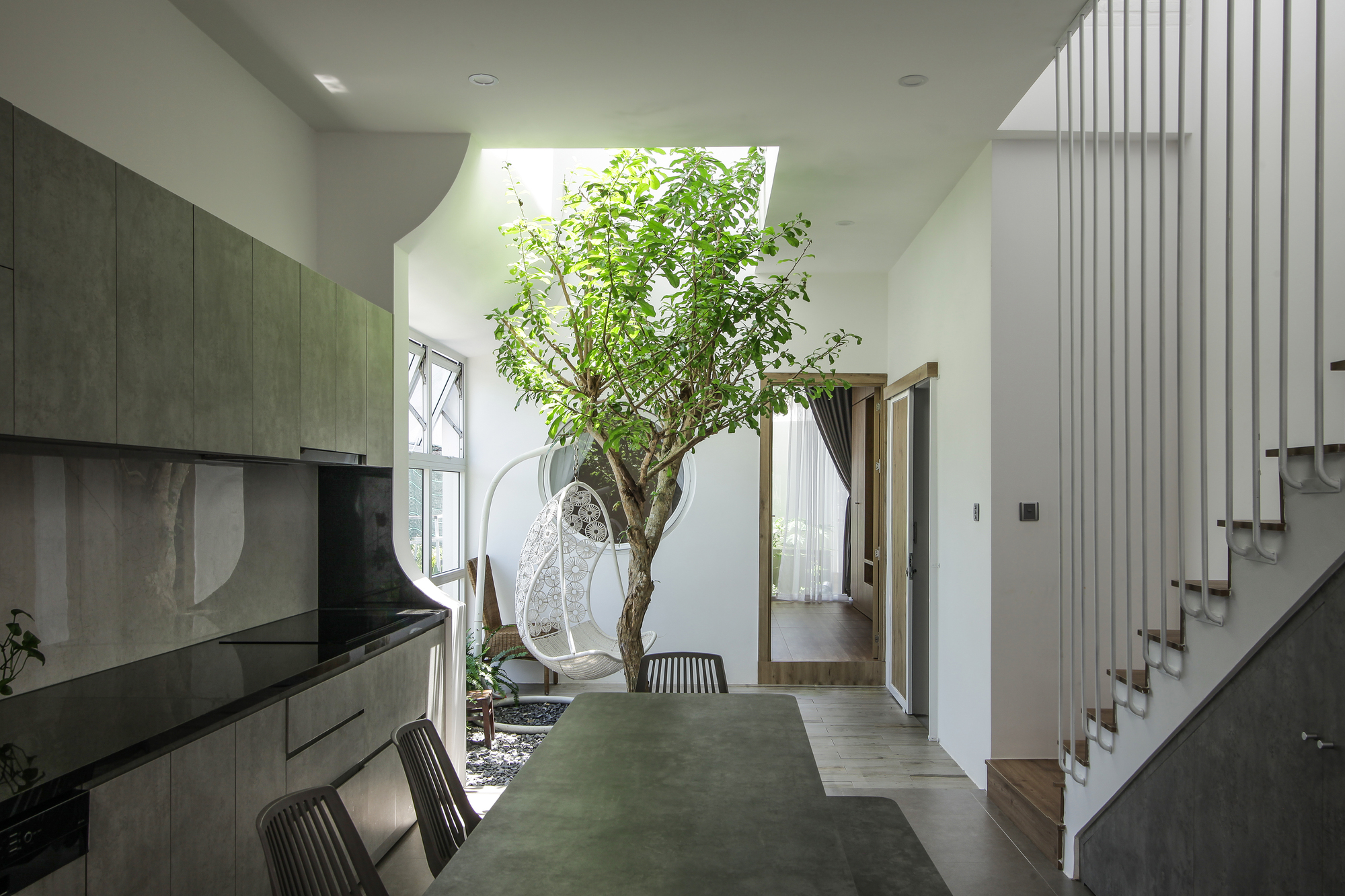 Next to the kitchen and dining room is a relaxing area with trees towering towards the skylights